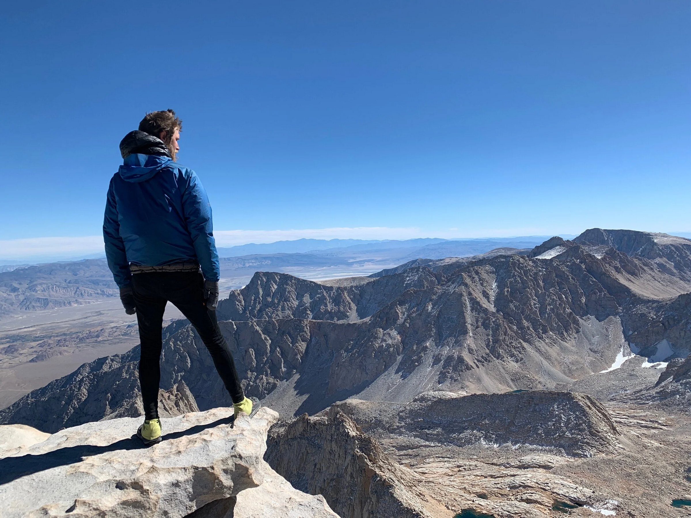 Jeremy Fillingim in a blue jacket on a rocky ledge on Mt. Whitney