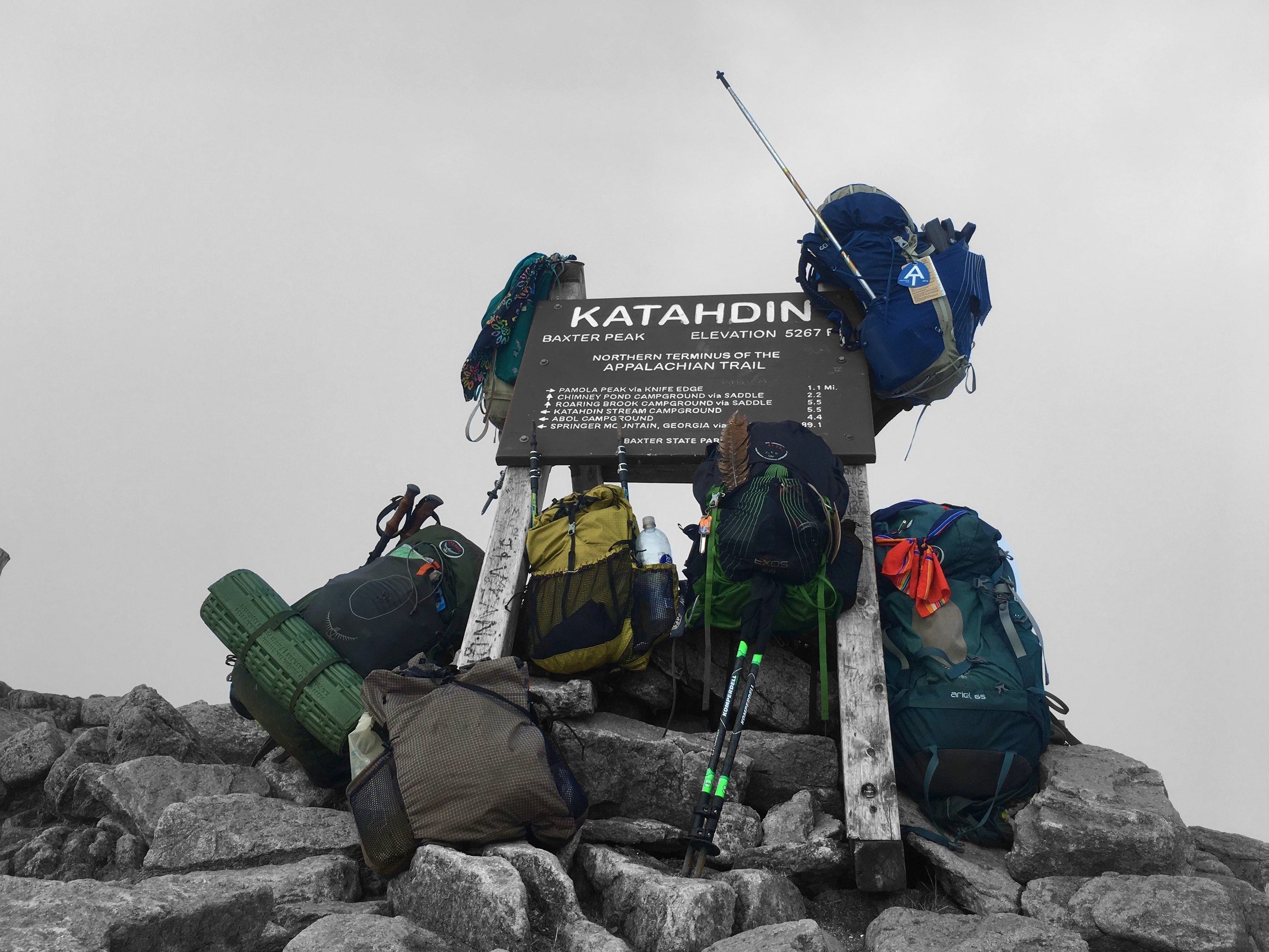 Katahdin summit sign surrounded by backpacks