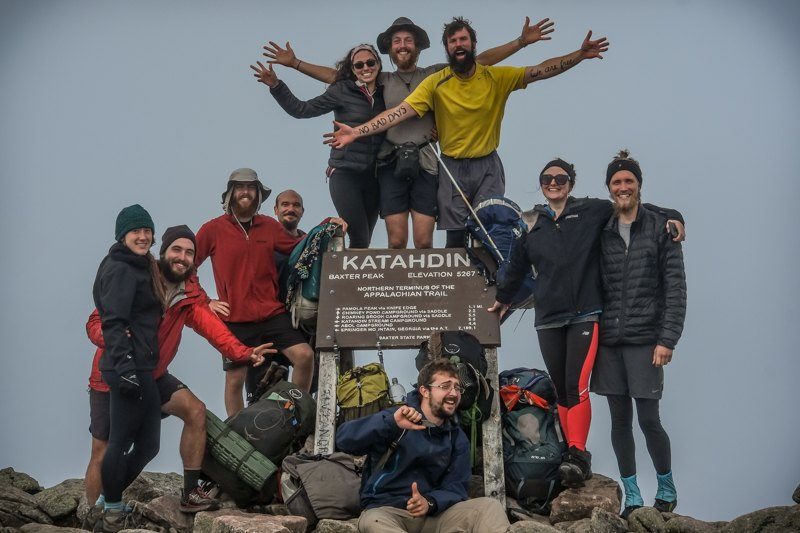 Hikers gathered at a summit sign