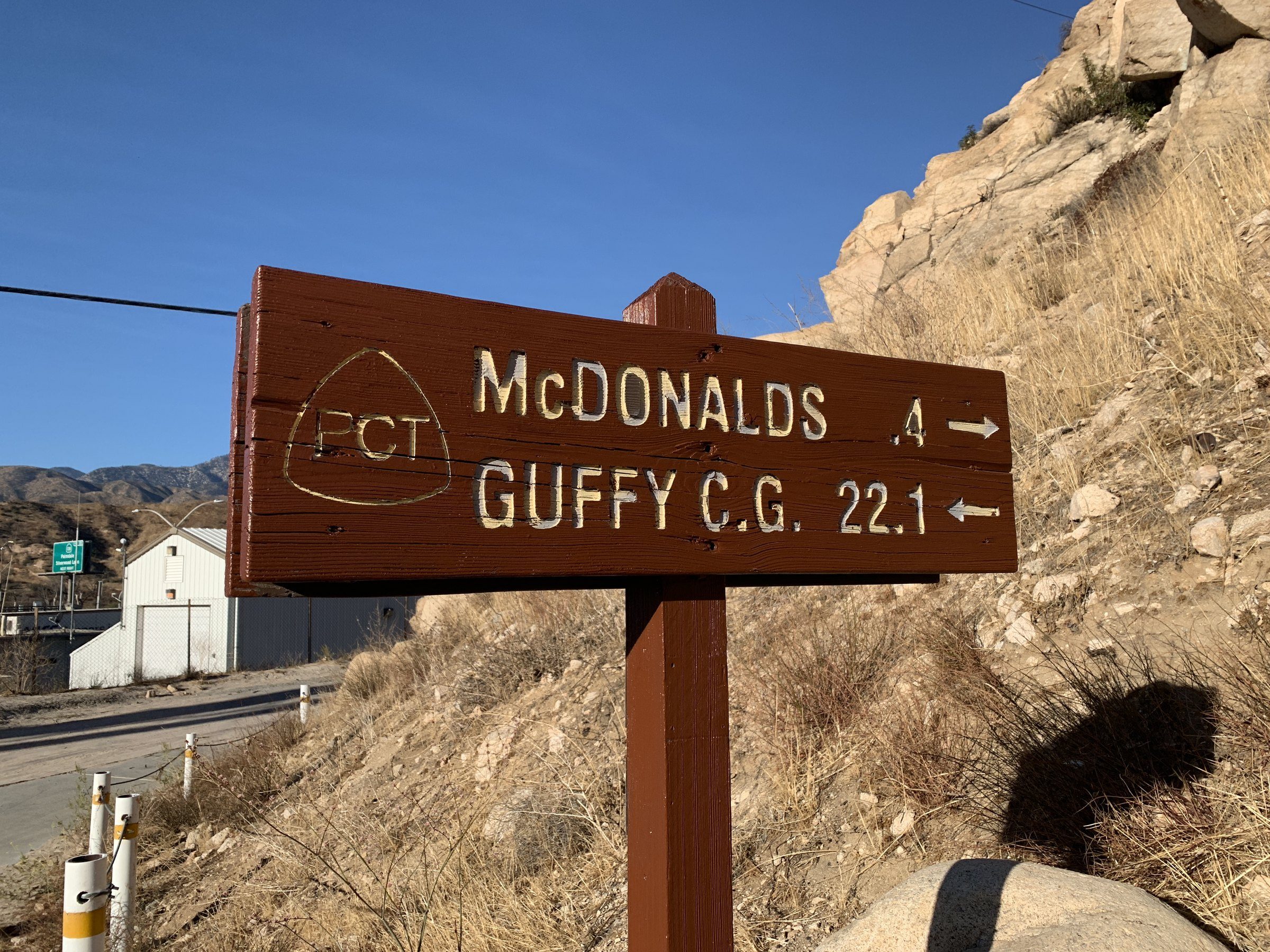 Weathered trail sign beside a road