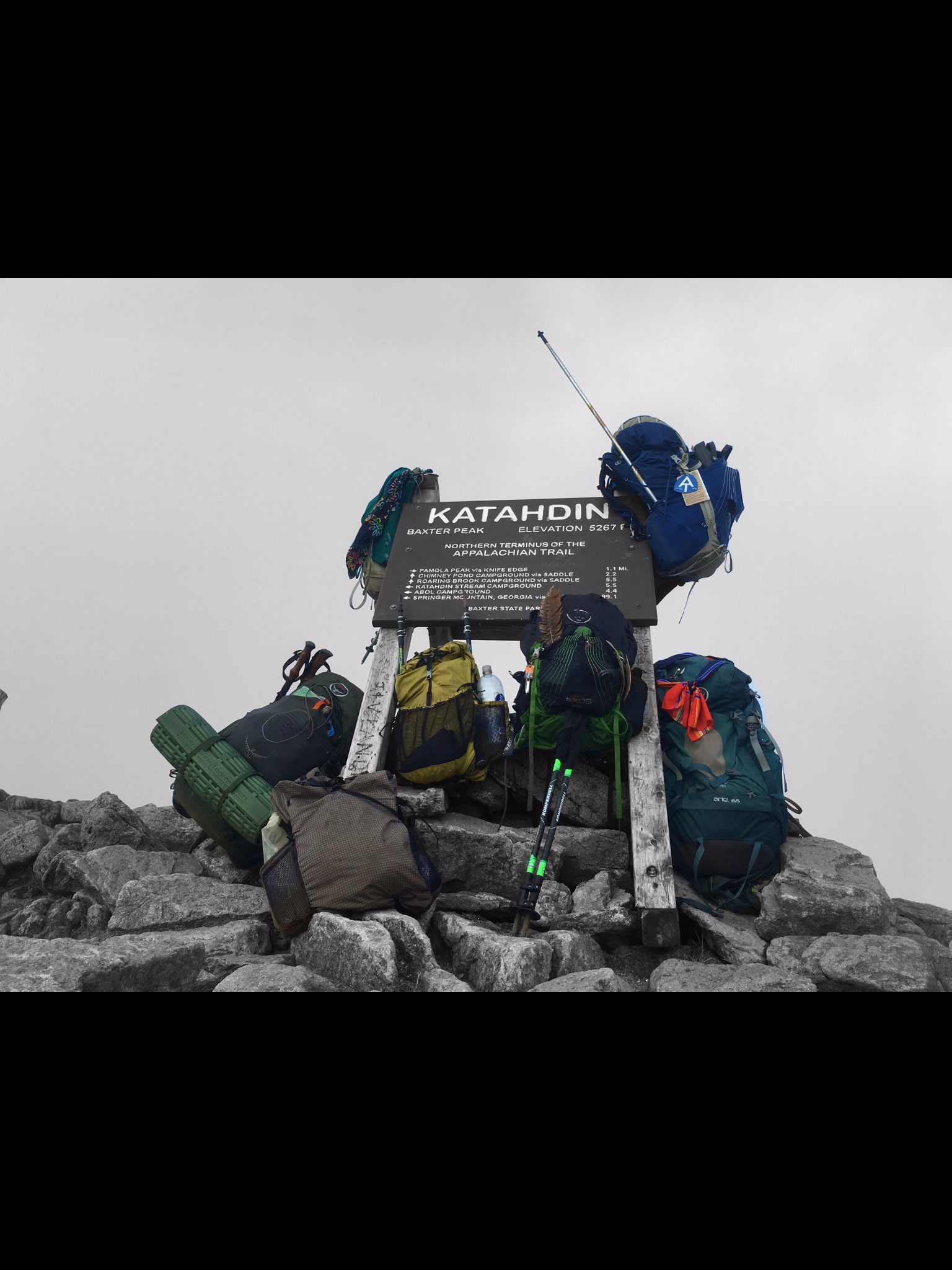Backpacks gathered around the Katahdin summit sign